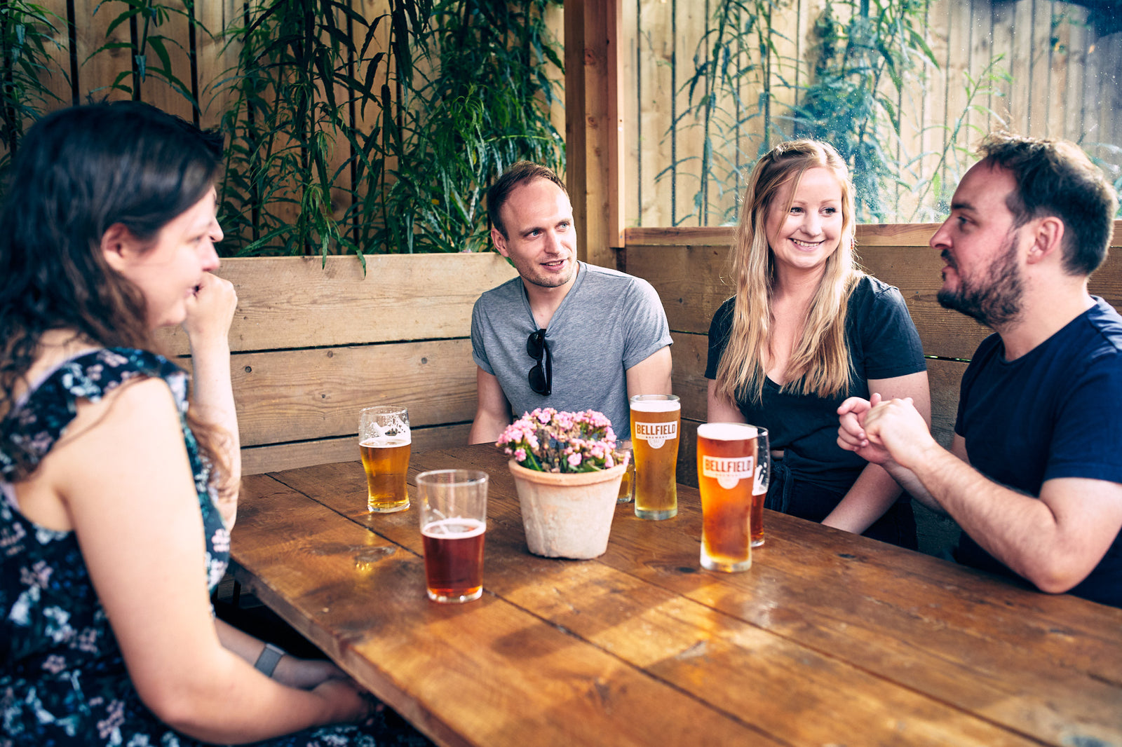 People sitting in a booth in a beer garden enjoying a pint