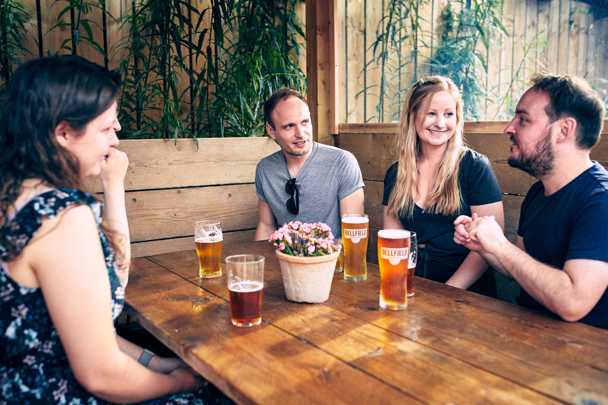 People sitting in a booth in a beer garden enjoying a pint
