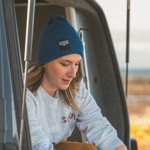 A girl wearing a blue Bellfield beanie hat.
