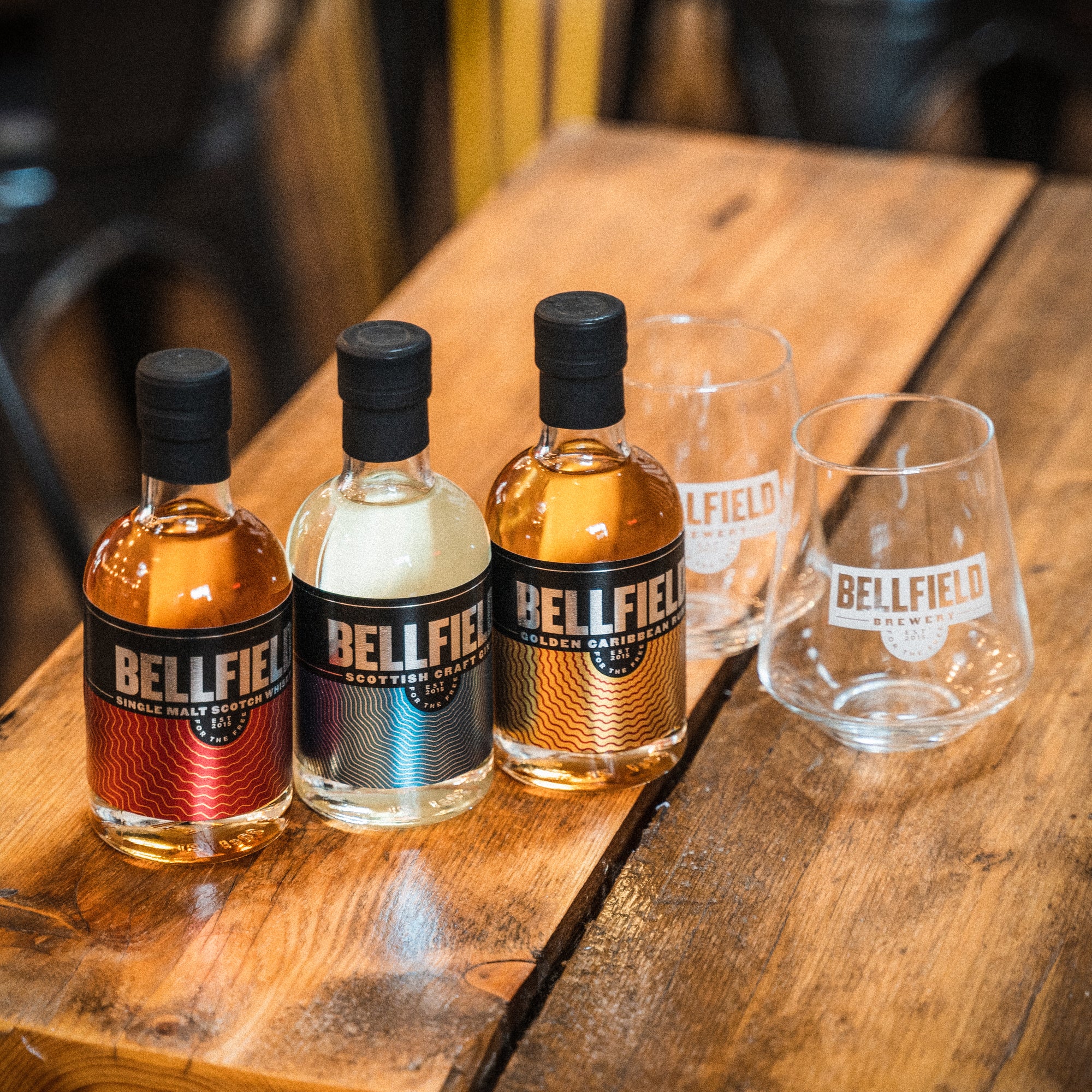 Three 20cl bottles of Bellfield Spirits with two tasting glasses.